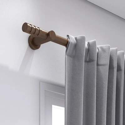 Varão de cortina bronze com ponteira decorativa e cortina cinza em ambiente moderno.