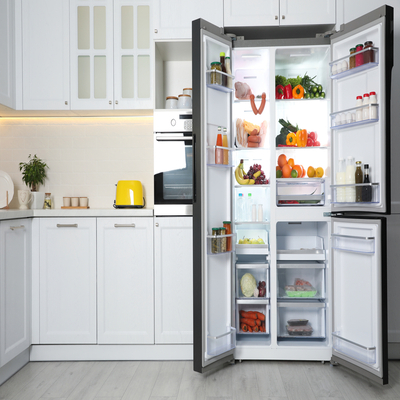 Geladeira frost free side by side com portas abertas, organizada com frutas, verduras, bebidas e alimentos em uma cozinha moderna e iluminada.