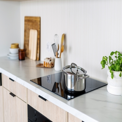 Cooktop de indução com panela de inox sobre bancada clara em cozinha minimalista, destacando praticidade, segurança e design moderno.