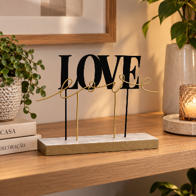 Adorno decorativo com a palavra LOVE em preto e dourado, disposto sobre estante de madeira em ambiente moderno.