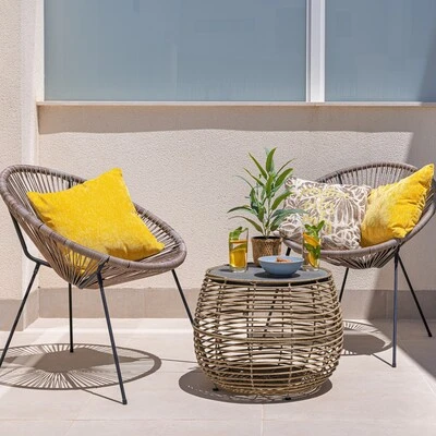 Almofadas amarelas para decoração de varanda e área externa Duas poltronas de fibra sintética com almofadas amarelas decorativas ao redor de mesa de centro em ambiente externo moderno.