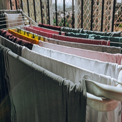 Varal portátil com diversas roupas estendidas em lavanderia, ideal para otimizar a secagem de roupas em ambientes internos ou externos.