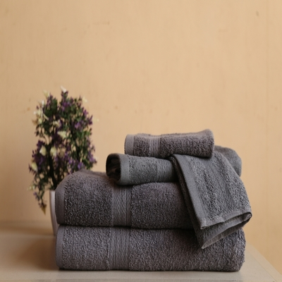 Conjunto de toalhas de banho brancas e bege dobradas sobre bancada de mármore, acompanhado de aromatizador de ambiente e decoração elegante.