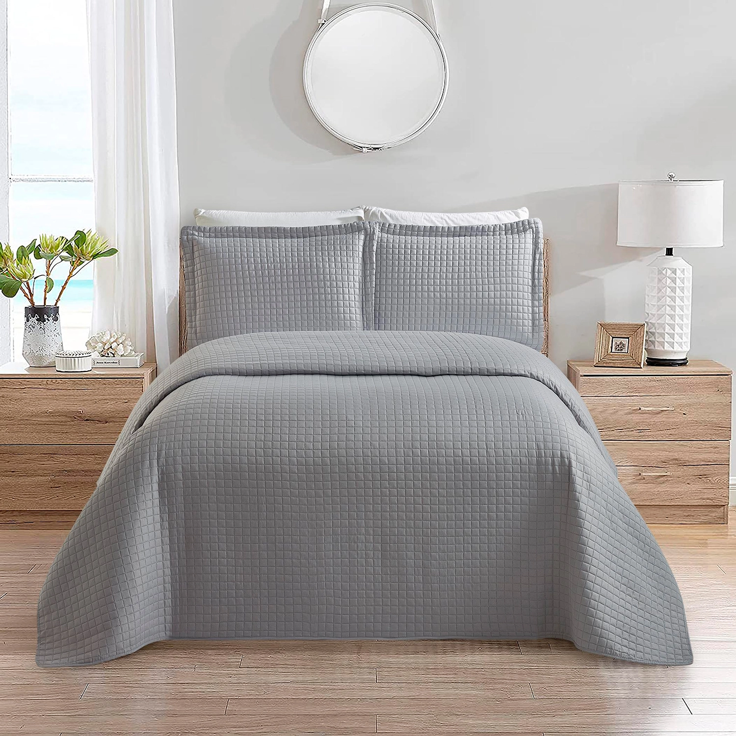 Colcha matelassê cinza com padrão geométrico sobre cama de casal em quarto claro e moderno.