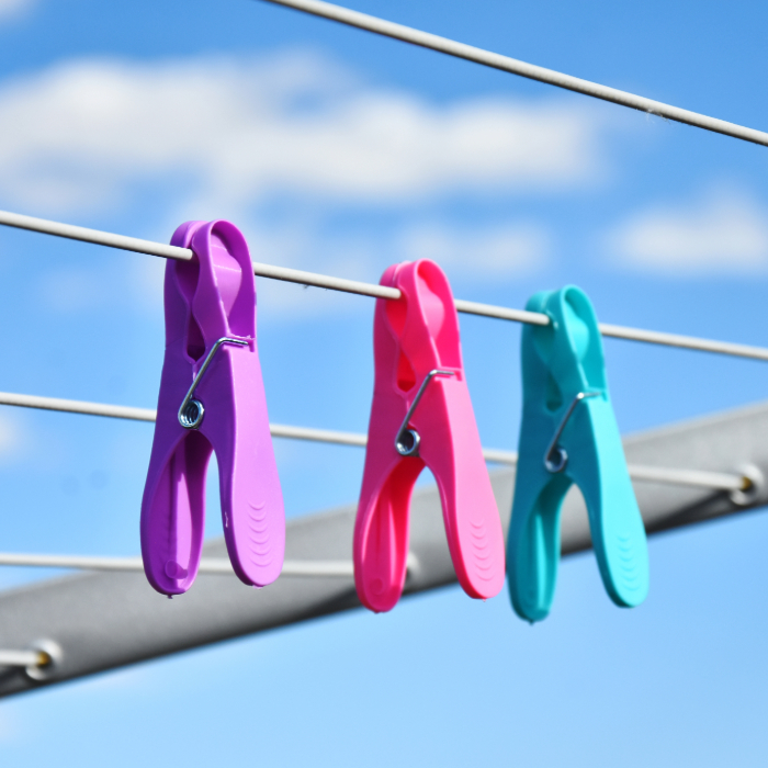  prendedores de roupa coloridos presos em fios de varal ao ar livre com céu azul ao fundo