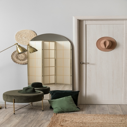 Espelho decorativo arredondado apoiado no chão em ambiente moderno, combinado com banco estofado, almofadas, luminária de piso e elementos decorativos.