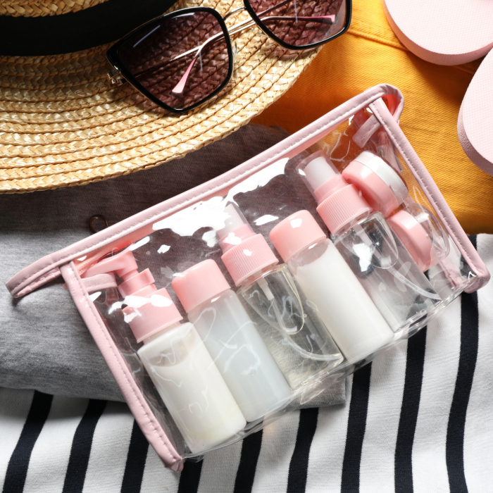 Kit de frascos de viagem em embalagem transparente com tampa rosa, ideal para levar cosméticos na mala de mão.